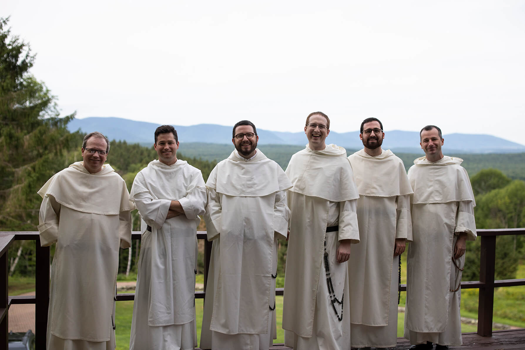 Dominican monks dressed in white habits standing in a row in front of green mountains bluegrass band photo